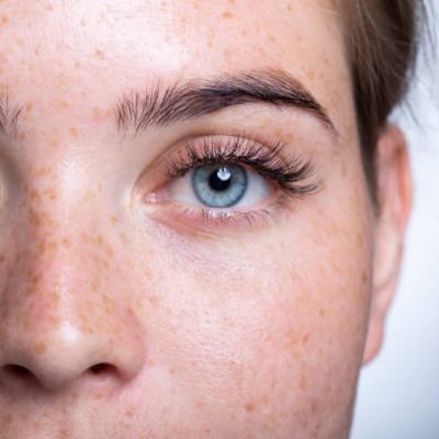 Cute skin girl with freckles, blue eyes. Looks at the camera. Portrait, close-up. On a white background.